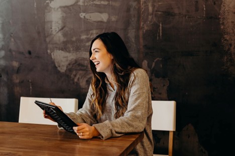 woman smiling looking at her tablet.