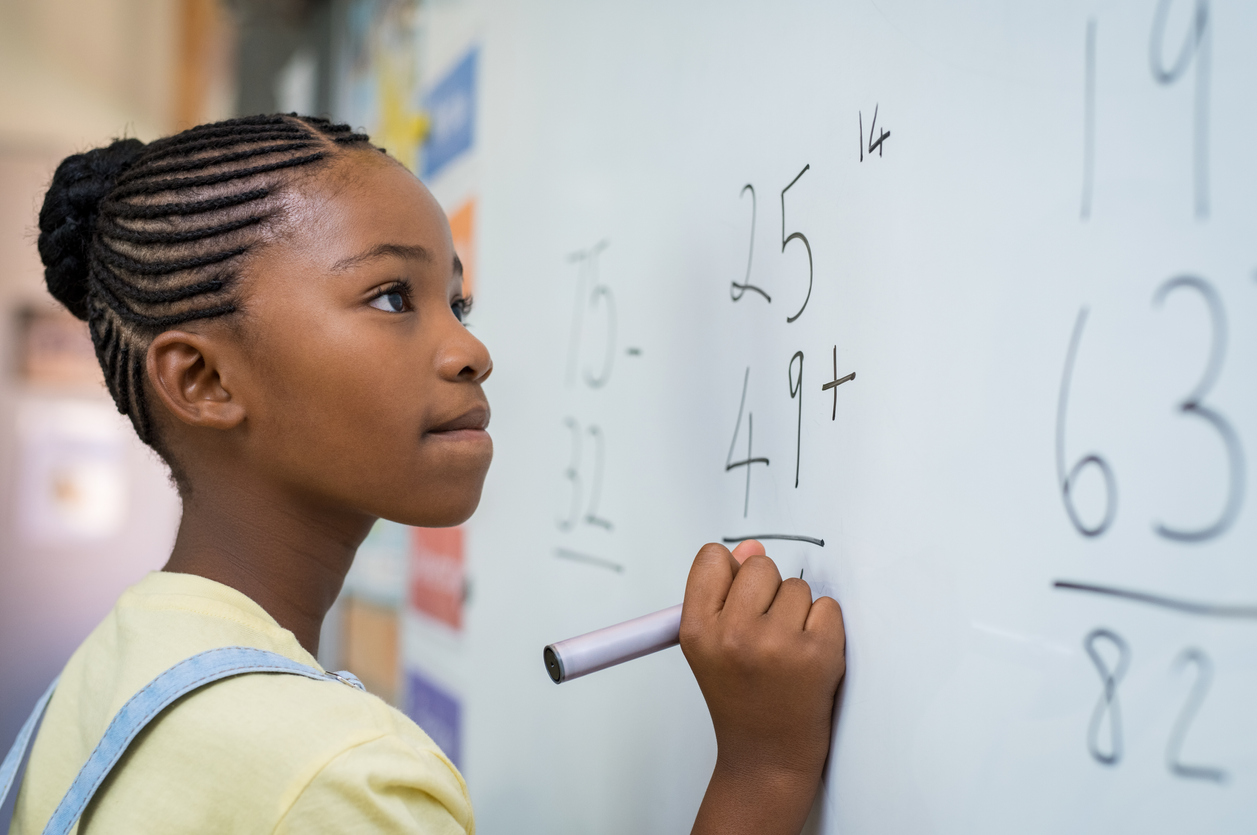 child doing math on a white board.